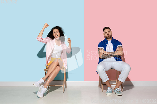 Image of Young emotional man and woman on pink and blue background