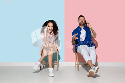Image of Young emotional man and woman on pink and blue background