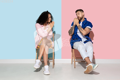 Image of Young emotional man and woman on pink and blue background
