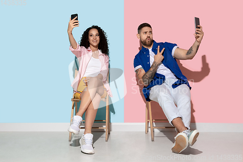 Image of Young emotional man and woman on pink and blue background