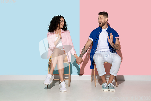 Image of Young emotional man and woman on pink and blue background