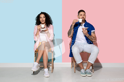 Image of Young emotional man and woman on pink and blue background