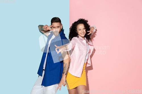 Image of Young emotional man and woman on pink and blue background