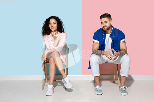 Image of Young emotional man and woman on pink and blue background