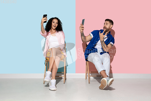 Image of Young emotional man and woman on pink and blue background