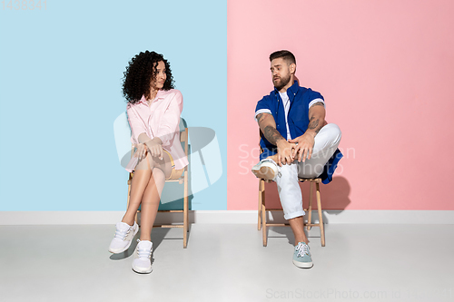Image of Young emotional man and woman on pink and blue background