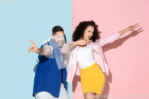 Image of Young emotional man and woman on pink and blue background