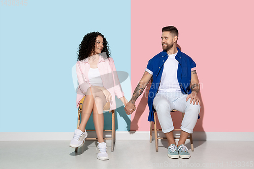 Image of Young emotional man and woman on pink and blue background