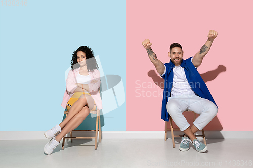 Image of Young emotional man and woman on pink and blue background