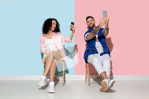 Image of Young emotional man and woman on pink and blue background