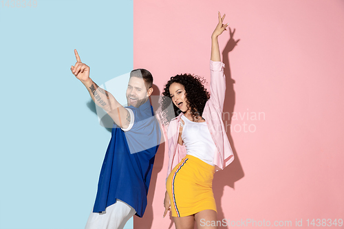 Image of Young emotional man and woman on pink and blue background