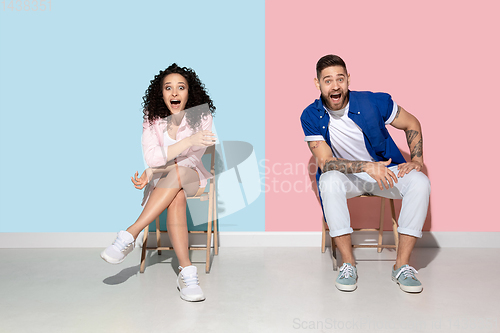 Image of Young emotional man and woman on pink and blue background