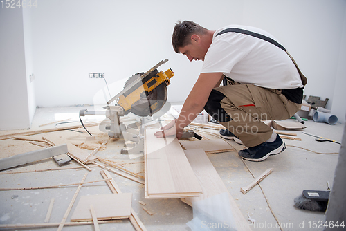 Image of Man cutting laminate floor plank with electrical circular saw