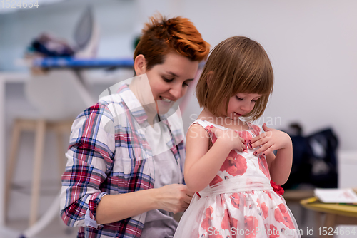Image of mother helping daughter while putting on a dress