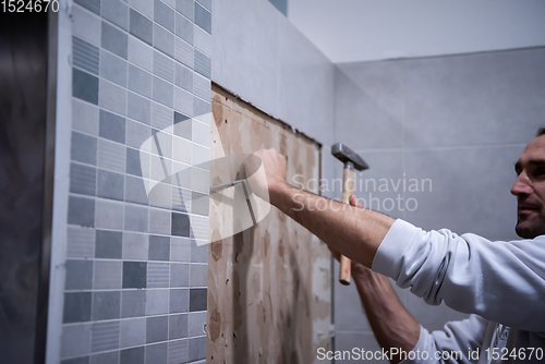 Image of worker remove demolish old tiles in a bathroom