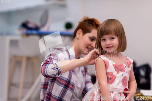 Image of mother helping daughter while putting on a dress