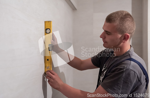 Image of professional plumber using bubble level in a bathroom