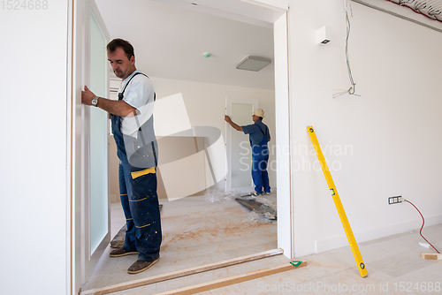 Image of carpenters installing glass door with a wooden frame