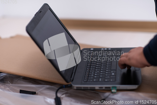 Image of man using laptop while lying on cardboard box