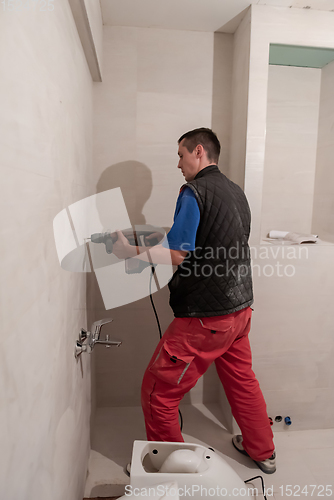 Image of construction worker drilling holes in the bathroom