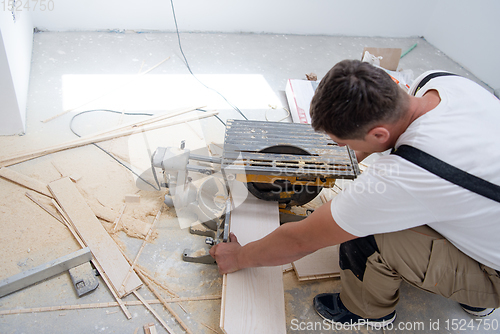 Image of Man cutting laminate floor plank with electrical circular saw