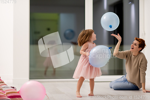 Image of mother and cute little daughter playing with balloons