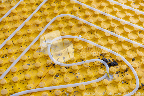 Image of yellow underfloor heating installation with white pipes