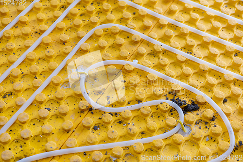 Image of yellow underfloor heating installation with white pipes