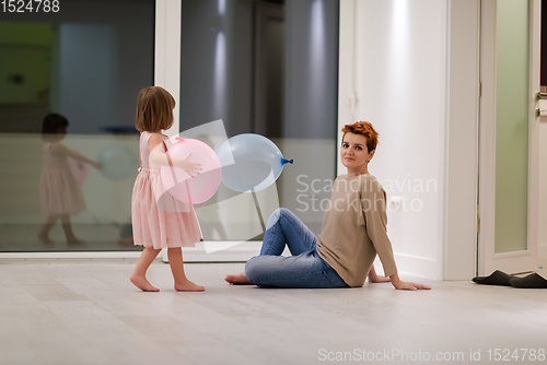 Image of mother and cute little daughter playing with balloons