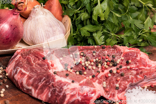 Image of steak of beef on a wooden board with spices pepper parsley salt 