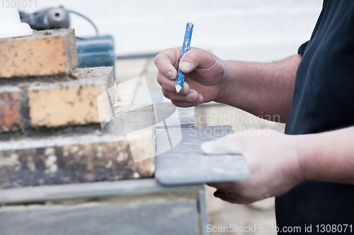 Image of the tiler measures and puts marks to cut and lay a tile