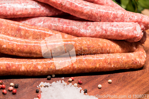 Image of raw sausages with chilli and herbs on a wooden board with spices