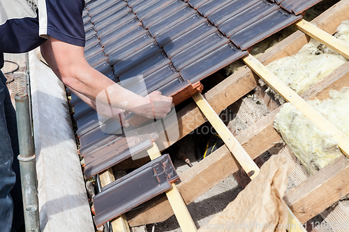 Image of a roofer laying tile on the roof