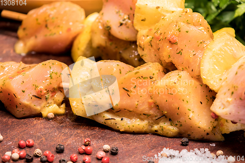 Image of raw chicken skewers marinated with lemon on a wooden board