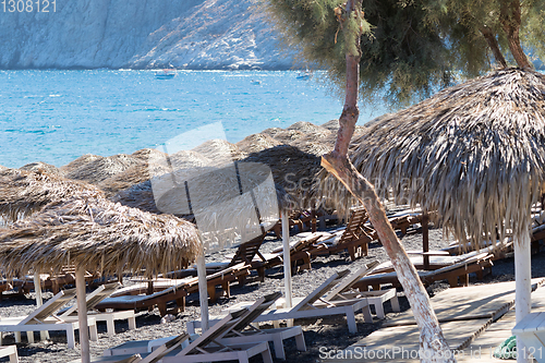 Image of beach with umbrellas and deck chairs by the sea in Santorini