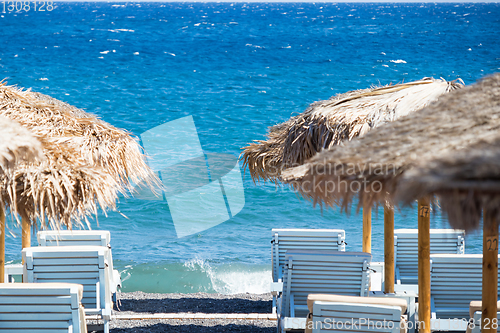 Image of beach with umbrellas and deck chairs by the sea in Santorini