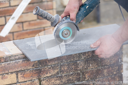 Image of tiler cutting a tile with a grinder