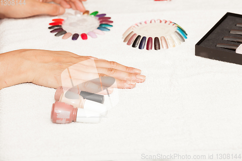 Image of Hands of a woman who chooses the color of her nail polish