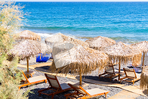 Image of beach with umbrellas and deck chairs by the sea in Santorini