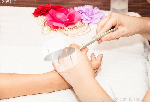 Image of The beautician polish the client\'s nails before putting nail polish
