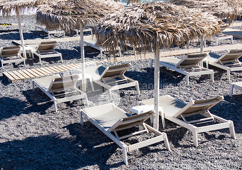 Image of beach with umbrellas and deck chairs by the sea in Santorini