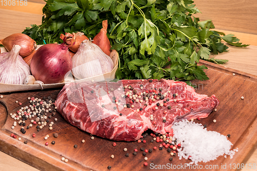 Image of steak of beef on a wooden board with spices pepper parsley salt 