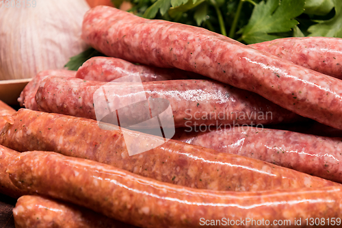 Image of raw sausages with chilli and herbs on a wooden board with spices