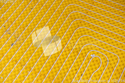 Image of yellow underfloor heating installation with white pipes