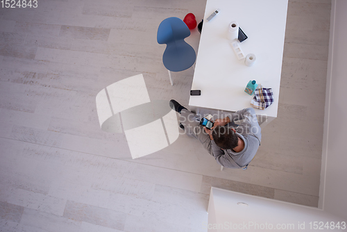 Image of top view of young painter in work suit using mobile phone