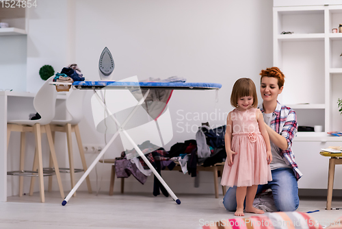 Image of mother helping daughter while putting on a dress