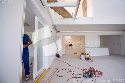 Image of carpenters installing glass door with a wooden frame