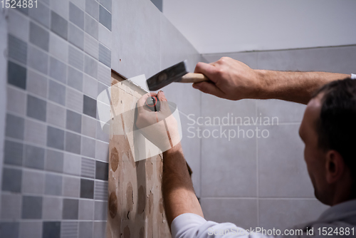 Image of worker remove demolish old tiles in a bathroom