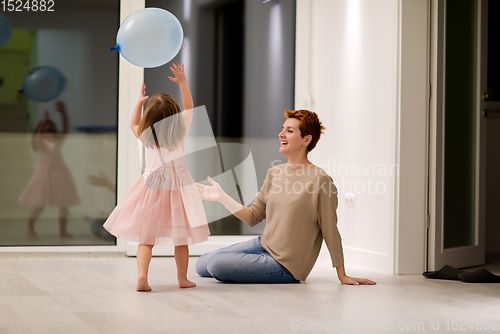 Image of mother and cute little daughter playing with balloons