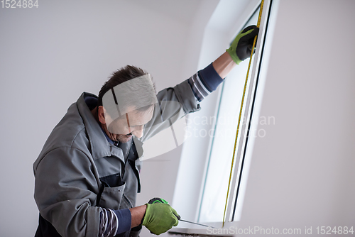 Image of man installing window with measure tape